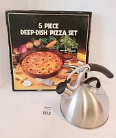 Photo showing 5-piece deep dish pizza set's original box with picture of cooked pizza and stainless steel kettle with black handle and spout lever.