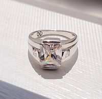 Front view of sterling silver ring showing large rectangular clear cubic zirconia and two smaller stones on each side against white background.
