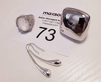 Photo of two rings and one pair of earrings on white surface with auction card number 73.