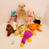 Front view of all 9 Ty Beanie Babies including bears, eagle, otter, chameleon, goldfish, duck, and bird, arranged on white background.