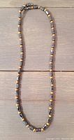 Hematite beaded necklace/bracelet laid flat on wooden surface, showing bead detail and gold-toned spacers.