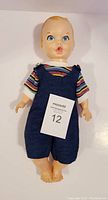 Front view of the vintage Gerber Baby doll lying down, showing its clothes and overall condition.