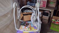 Baby swing fully assembled with three baby books placed on the seat.