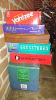 Stack of five board games including Yahtzee, I.N.I.T.I.A.L. Response, Guesstures, Scattergories, and an unidentified game.
