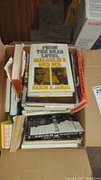 Box of various books including biographies and non-fiction, showing 'From the Dead Level: Malcolm X and Me' on top.