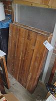 Two wood butcher blocks leaning against a screen door in a garage or storage area, showing natural wood grain and surface wear.