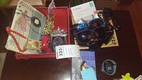 Overview photo showing costume jewelry, sunglasses, Fitbit in box, and book on table surface