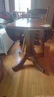 Wooden drop leaf table shown from the side, illustrating drop leafs and tabletop surface.
