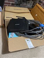 Box containing Netgear Wi-Fi boosters, cables, and a Kenwood branded box.