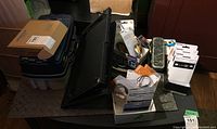 Overview of lot showing boxed and loose items on table including toolbox, boxed cables, and packaged speaker covers