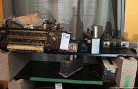 Photo showing a variety of vintage electronic components including a radio, tube amplifier parts, and transformers placed on shelves.