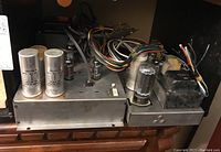 Photo showing metal chassis with multiple vacuum tubes, two large silver capacitors labeled 105-15-10 MFD, wiring harness, and transformers.