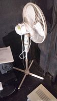Photo of full standing white Hampton Bay oscillating floor fan showing base, blades, and controls.