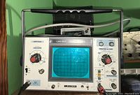 Front view of the Leader LBO-507 oscilloscope showing CRT screen, vertical and horizontal controls, power switch, and input connectors with handle on top.