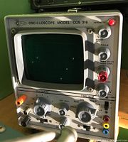 Front view showing oscilloscope CRT screen, control knobs, and jacks