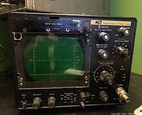 Front angle showing full CRT screen with calibration grid and multiple control knobs.