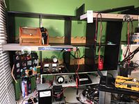 Full shot of the black 8-cube shelf screwed to a white riser, filled with wooden bread box shelf, electronic meters, and toolboxes.