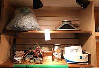 Two shelves with electronic parts in boxes and jars, with one speaker wrapped in bubble wrap on top shelf