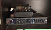 Front view of DBX 1215 graphic equalizer showing dual channel sliders and controls.