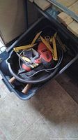 Top view of tote bin filled with assorted hand tools including Black & Decker electric drill, caulking applicators, handles of tools visible