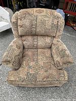 Front view of arm chair showing patterned upholstery and deeply cushioned seat and back with movable cushions and padded armrests