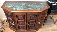 Console table with dark wood finish, veined white-green marble top, four paneled cabinet doors with brass handles