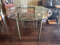 Full view of round glass top dining table showing tabletop and metal base.