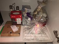 Overall view of assorted giftware including boxed ceramic items, wrapped gifts with ribbons, metal salt and pepper shakers on stand, and smaller ceramic pieces.