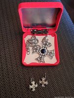 Silver-tone cross pendant necklace with rhinestones and matching earrings in red jewelry box