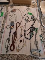 Photo of multiple necklaces laid on a white cloth showing variety of chains, beads, and pendants.