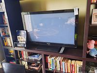 Panasonic 42 inch LED TV on shelf with remote on stand, surrounded by books and toys.