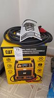 CAT CJ1000DCP professional power station in box with jumper cables and instruction manual on top