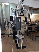 Full view of the Weider Power Max Cross Trainer Home Gym showing its white frame, padded seat, weight stack, pulleys, and handles.