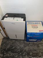 Front view of Soleus Air dehumidifier and a Venta-Sonic ultrasonic humidifier box next to it, focus on Soleus unit.