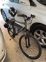 Side view of gray Maverick mountain bicycle between cars in garage, showing overall frame and tires.