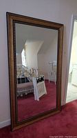 Large floor-standing rectangular mirror with decorative gold-tone frame.