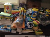 Overview photo showing assorted cleaning supplies including paper towels, boxes of detergents, and cleaning cloths.