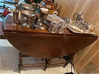 Side view of wooden drop leaf table showing closed leaf and items on top (not included).