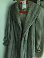 Full front view of the vintage long fur jacket hanging on a red hanger, showing the full length and sleeve details.