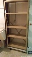 Full view of beige metal shelving unit showing five shelves and overall structure.