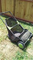 Complete view of the Earthwise lawn sweeper showing black and green body with mesh collection bag and handlebar.