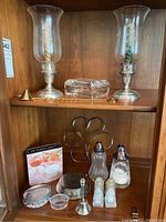 Full view of shelf showing the candle holders with spiral candles, smaller items including coasters, bell, salt and pepper shakers, sugar shaker, and glass dishes.