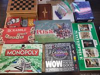 All board games and card games arranged on floor including Scrabble, Risk, Monopoly, Cranium, Masterpiece, Magic: The Gathering, Pit, and Hit Deck boxes.