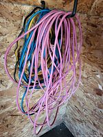 Several colorful extension cords coiled on hooks, including pink, blue, yellow, and black cords.