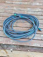 Blue garden hose coiled neatly with connectors at both ends on wooden deck.