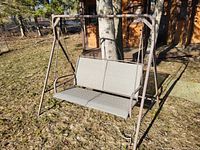 Photo of large outdoor metal swing with textured metal seating and rust on frame