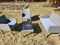 Outdoor shot showing two armchairs, one loveseat, and a coffee table arranged on grass.