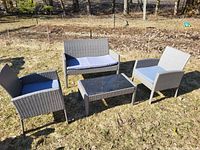 All components of grey wicker patio set displayed on grass