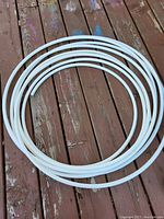 Coiled white PEX tubing laid out on wood deck showing full length coil