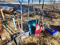 Photo of multiple garden tools including two snow shovels, leaf rake, pitchfork, garden fork, and a tool with blue handle